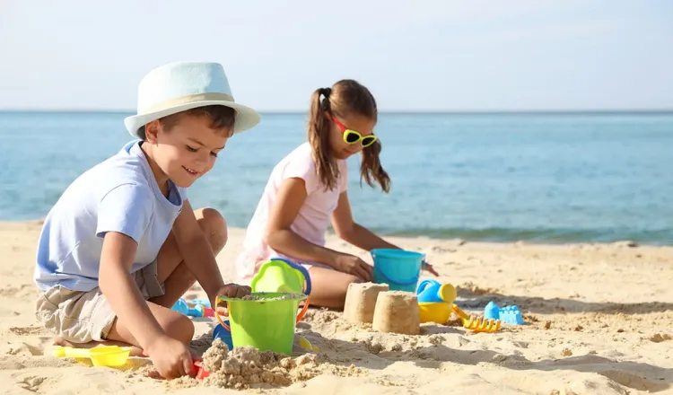 Kinder bauen Sandburgen am Strand der Ostsee während des Sommerurlaubs