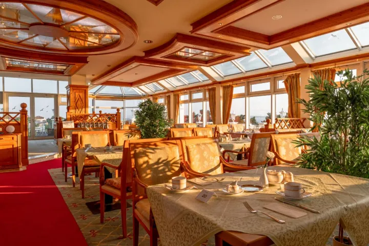 Der weitläufige, elegant eingerichtete Essbereich mit Stühlen, Tischen und Panoramafenstern im Restaurant Königsstuhl.