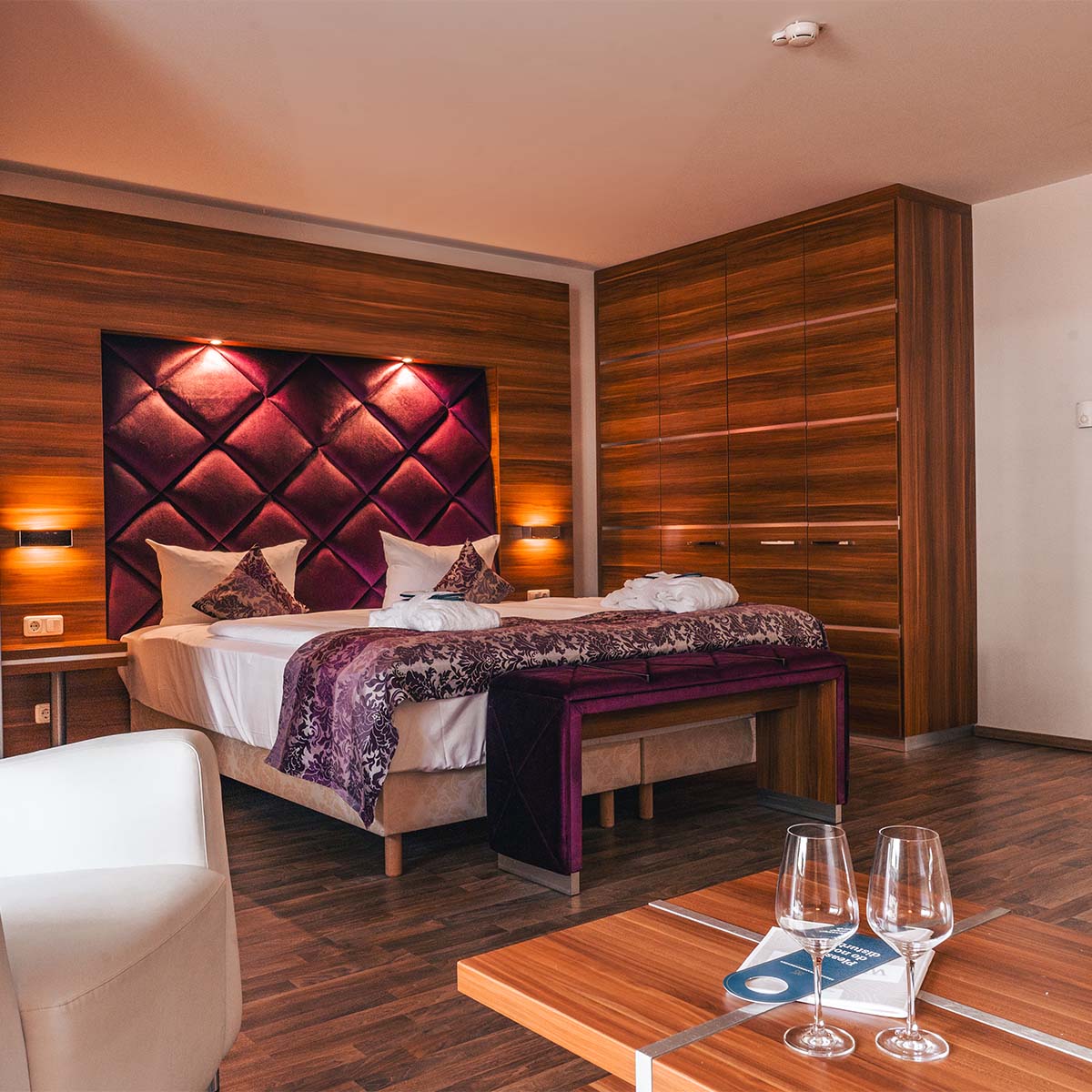 Doppelzimmer in der Ferienwohnung in Binz auf Rügen mit großem Doppelbett, lila Akzenten und Holzmöbeln.