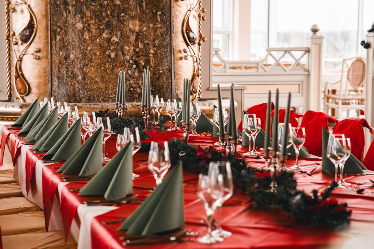 Ein festlich geschmückter Tisch mit Servietten, Kerzen, Weingläsern und Bestecken in den Arkona Strandresidenzen zur Weihnachtszeit.