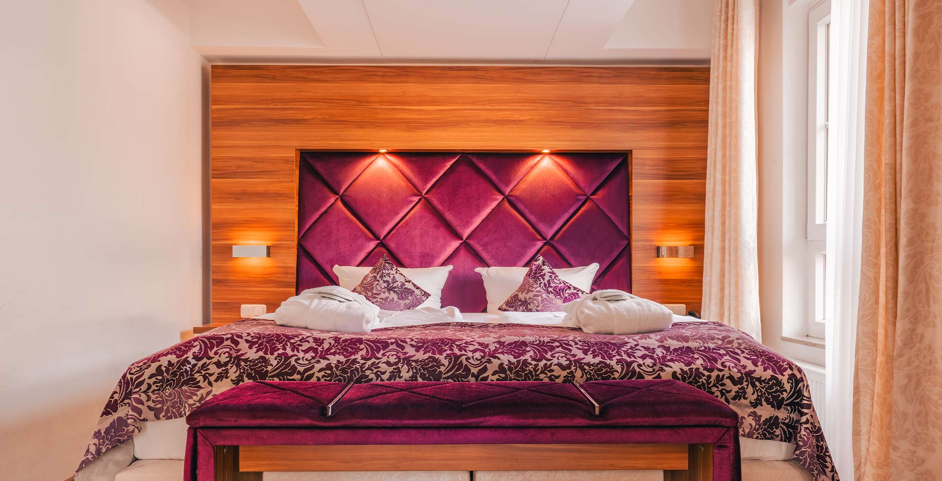 Elegantes Doppelbett mit violettem Polsterkopfteil im Apartment Hotel auf Rügen.