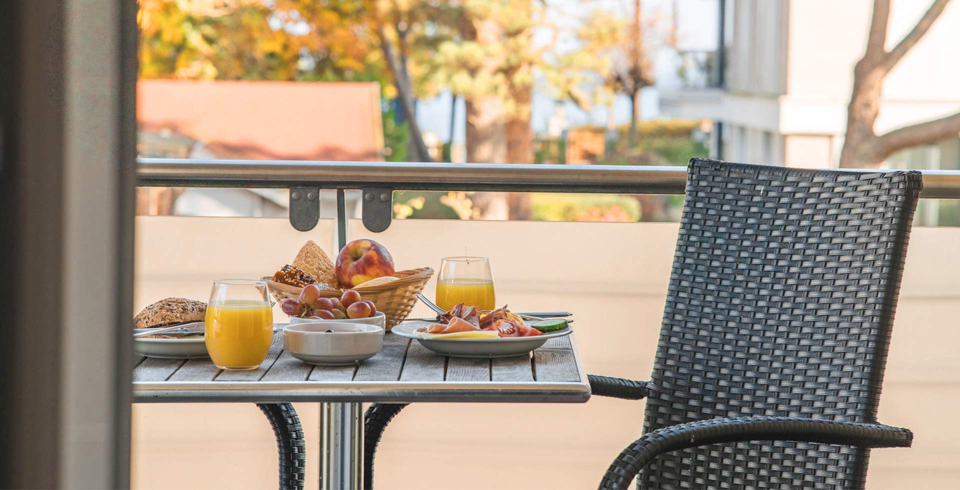 Frisches Frühstück mit Saft, Brötchen und Obst auf dem Balkon im Apartment Hotel auf Rügen.