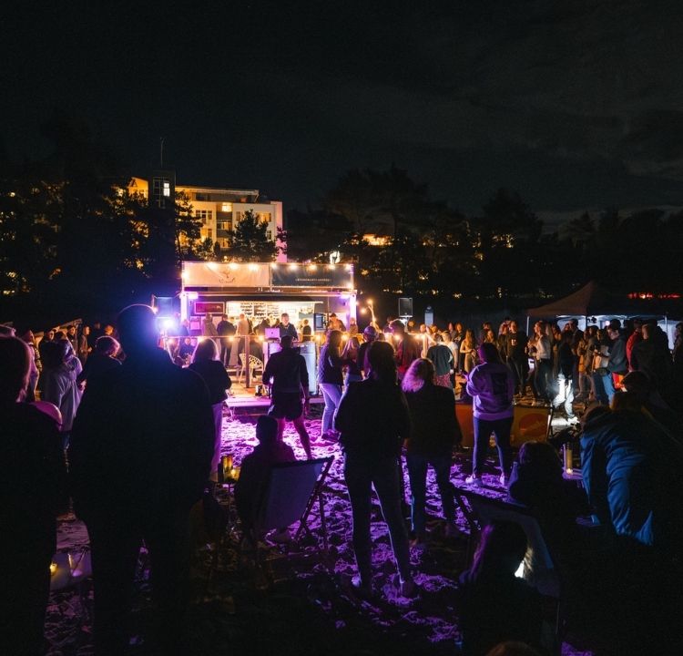 Menschen beim Tanzen zu Musik vom DJ beim großen Saisonfinale am Strand von Binz – perfekte Beats für eine unvergessliche Nacht.