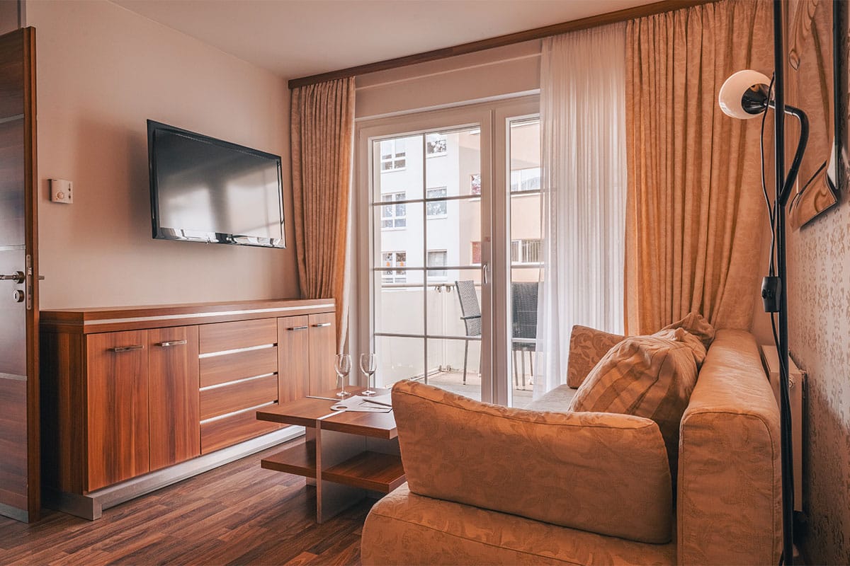 Wohnzimmer im Apartment der Arkona Strandresidenzen Binz mit Sofa, TV und Zugang zum Balkon