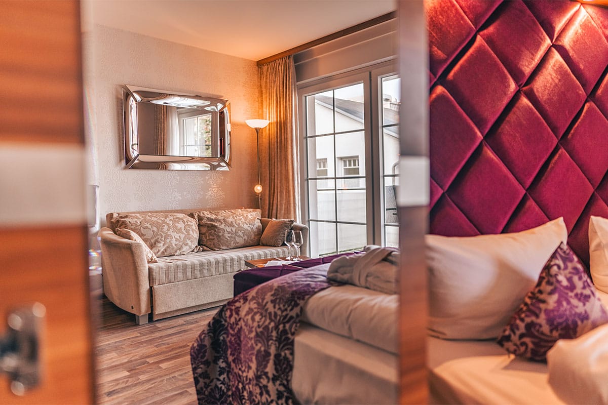 Sitzecke im Deluxe Apartment der Arkona Strandresidenzen Binz mit Sofa, Beistelltisch und großem Fenster zum Balkon