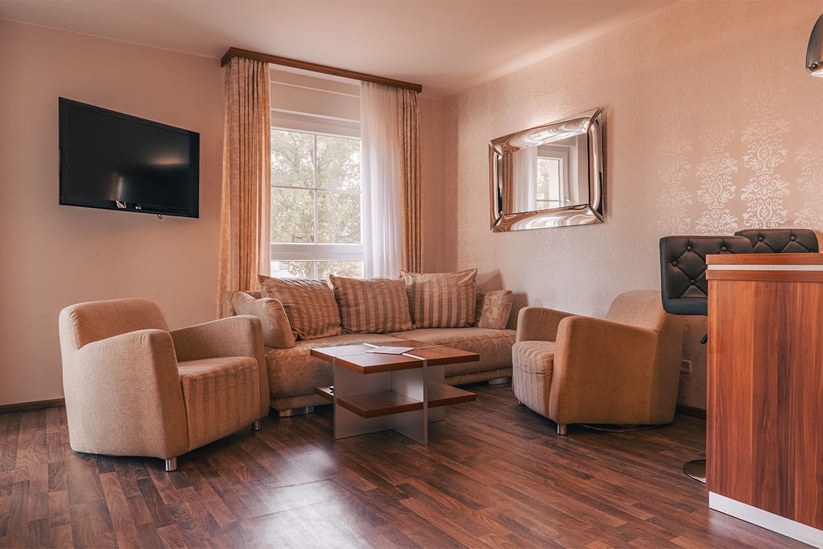 Wohnbereich im Suite Apartment der Arkona Strandresidenzen Binz mit Sofa, Sesseln, Couchtisch und Fernseher