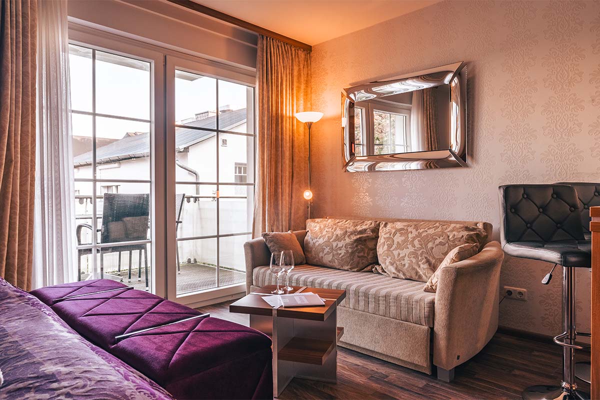 Wohnbereich mit Sofa, Couchtisch und Blick auf den Balkon im Studio der Arkona Strandresidenzen