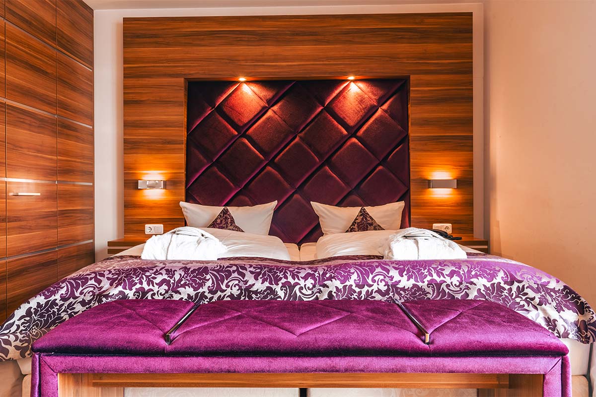 Blick auf das Doppelbett mit violettem Kopfteil und Tagesdecke im Studio in Binz