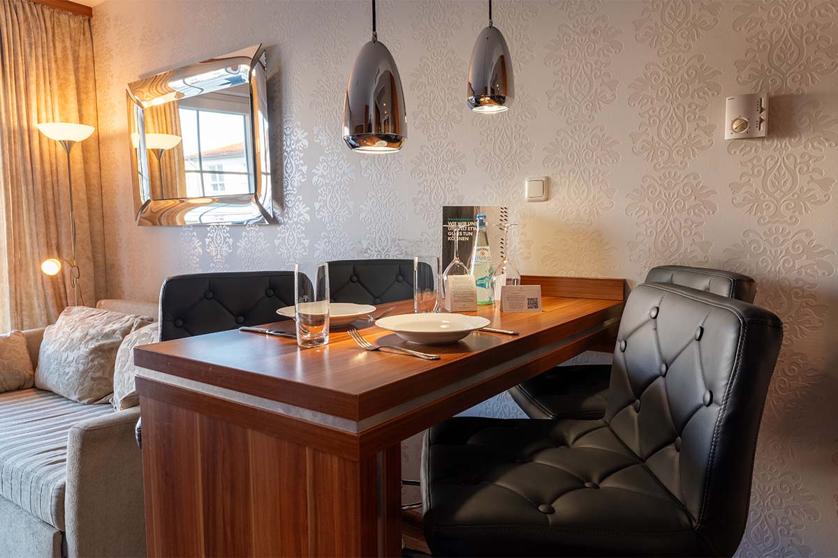 Essbereich mit gedecktem Tisch und zwei Polsterstühlen im Studio der Arkona Strandresidenzen