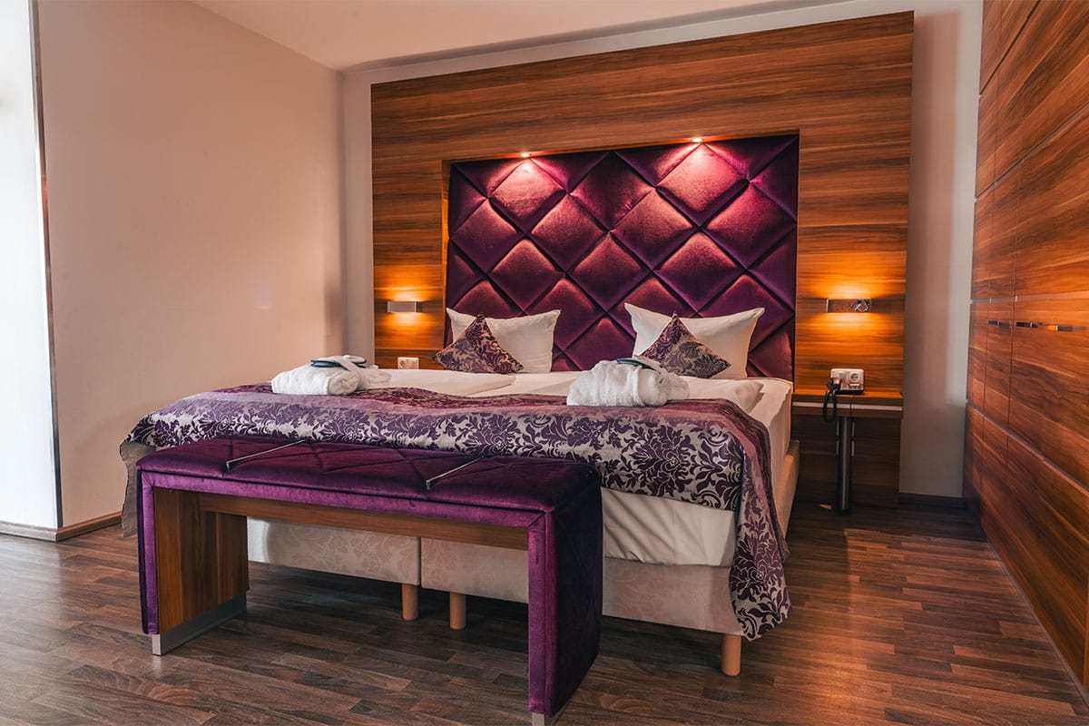 Doppelbett im Superior Studio des Arkona Strandresidenzen Binz mit gepolstertem Kopfteil und indirekter Beleuchtung