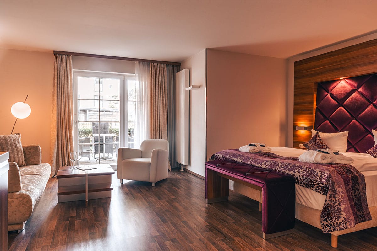 Überblick über das Superior Studio im Arkona Strandresidenzen Binz mit Doppelbett, Sofa und Balkonzugang