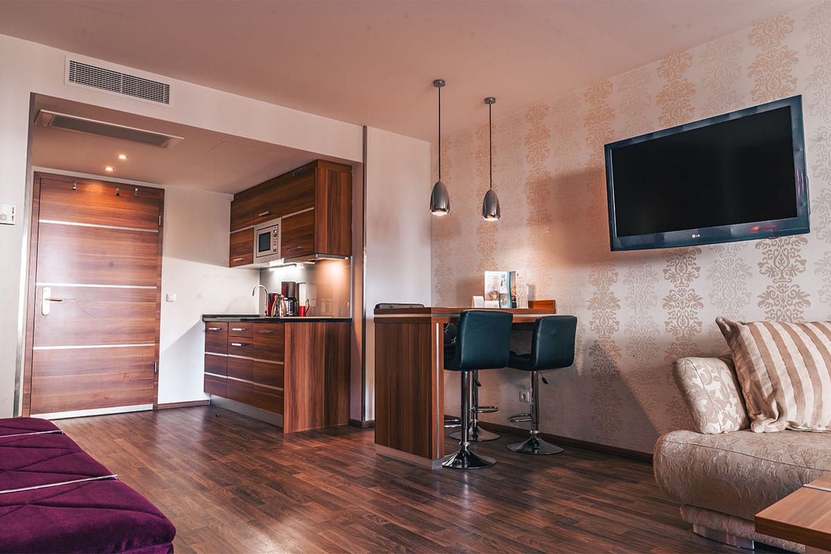 Küchenzeile mit Essbereich, Fernseher und Couch im Superior Studio der Arkona Strandresidenzen Binz