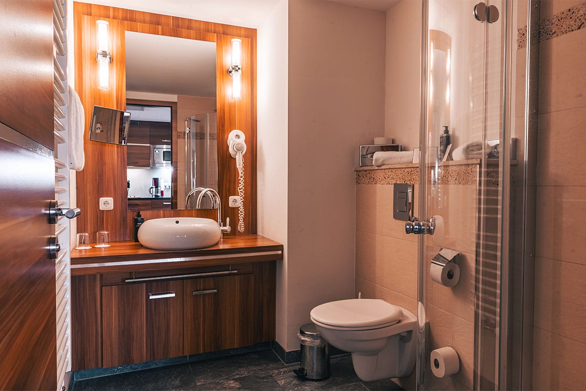 Badezimmer im Superior Studio der Arkona Strandresidenzen Binz mit Glasdusche, Waschbecken und großem Spiegel